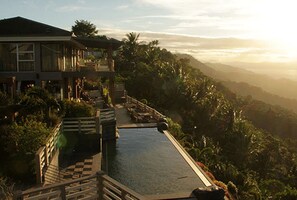 Um resort com piscina, deck de madeira e vegetação exuberante.