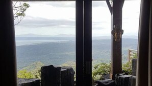 Una habitación con un gran ventanal que da a una terraza y vistas de un paisaje montañoso.
