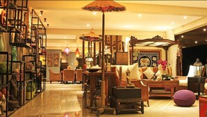Un vestíbulo amplio y bien iluminado, con diversas opciones de asiento, incluyendo sofás y sillones, y una pared decorativa con diseños intrincados.