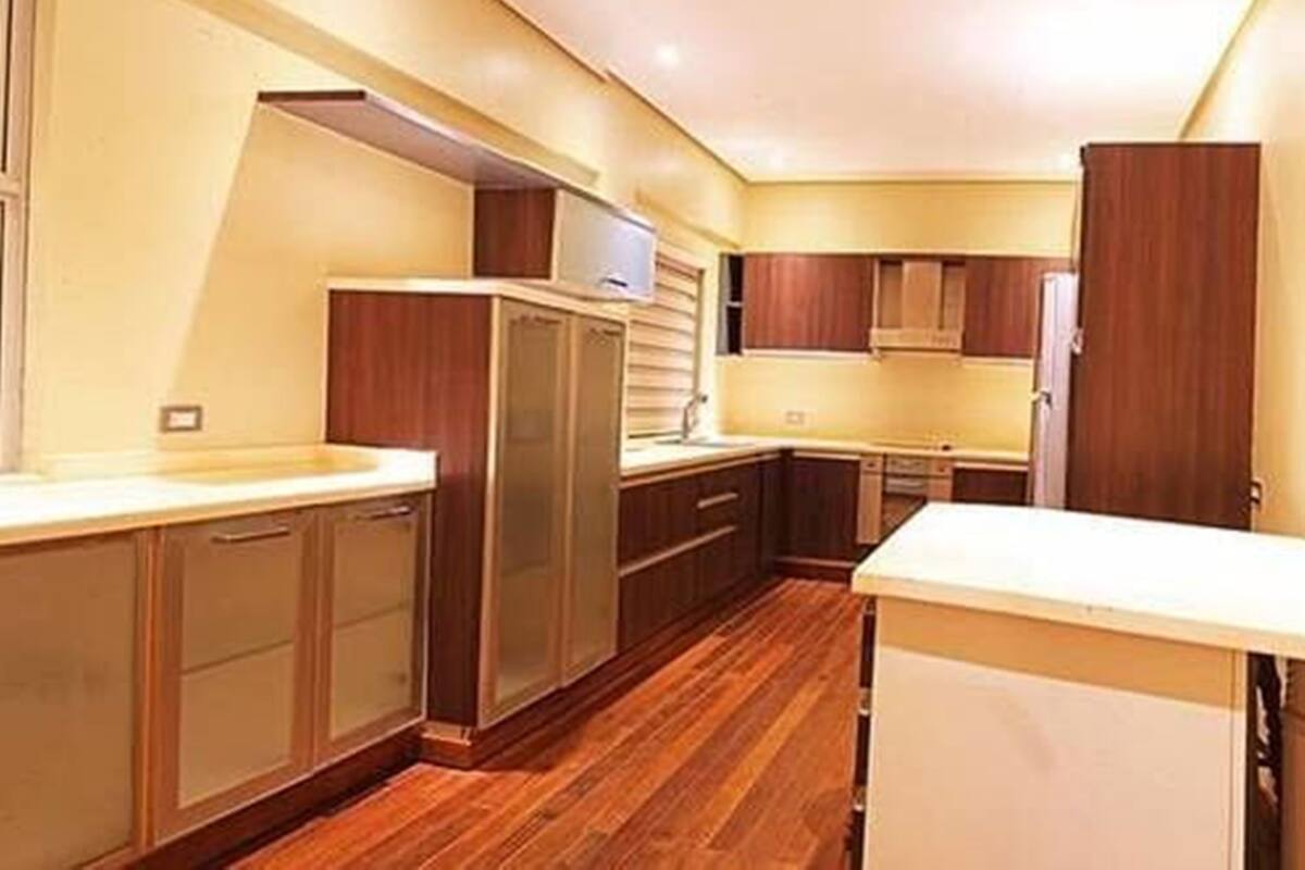 A compact kitchen with wooden cabinets, a built-in oven, and a white countertop.