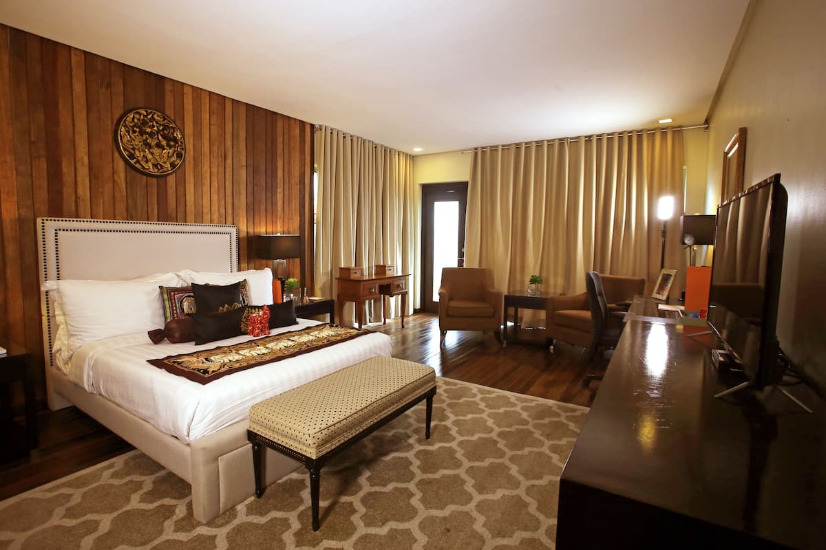 A hotel room with a large bed, a desk, a chair, and a TV.