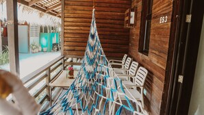 A wooden cabin with a thatched roof, a hanging hammock, and a table with chairs. - Seasta Beach Resort (Baler)