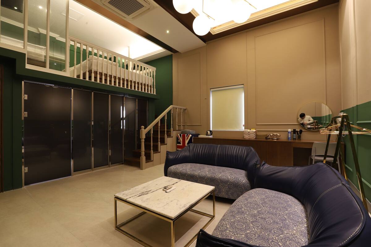A modern hotel room with a balcony, a sofa, a small table, and a desk with a mirror.