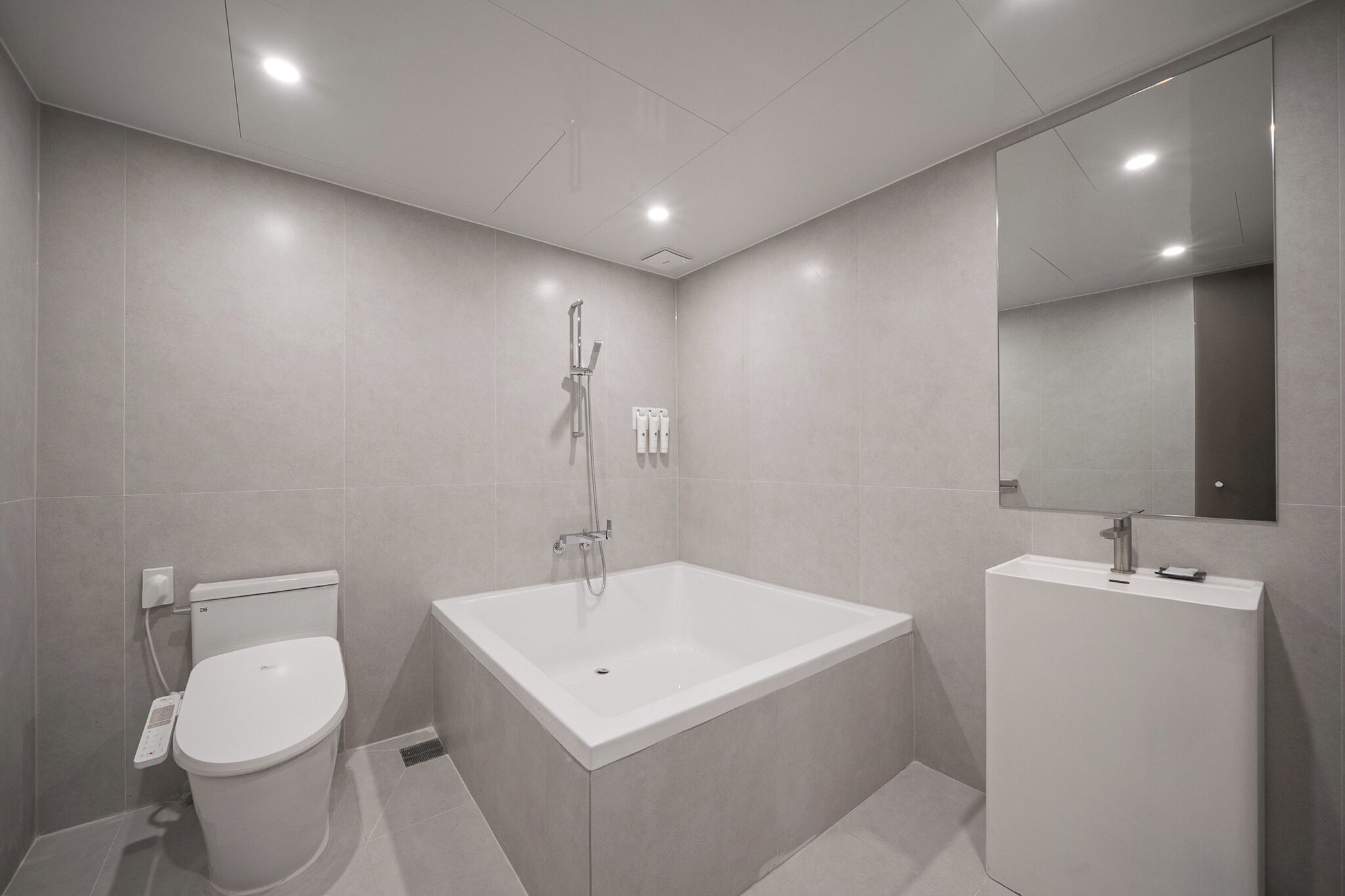 A modern bathroom with a toilet, a bathtub, and a sink.