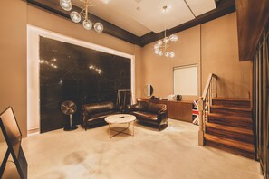 A spacious living room with a large black marble wall, a leather sofa, a coffee table, and a staircase.