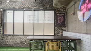 A brick wall with a large window, a neon sign, and a table with chairs. - ACT호텔 어반 (Daegu)