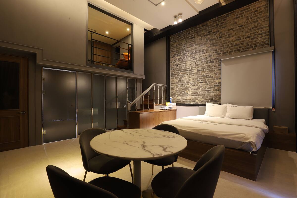 A modern hotel room with a bed, a marble table, and chairs.