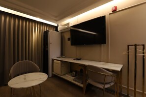 A compact hotel room with a kitchenette, a flat-screen TV mounted on the wall, a small refrigerator, a dining table with two chairs, and a coat rack. - Hotel Yeogiuhtte Daegu Station (Daegu)