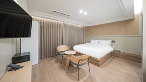 A hotel room with a bed, a desk with a computer, a chair, a small table, and a TV. - ACT호텔 어반 (Daegu)