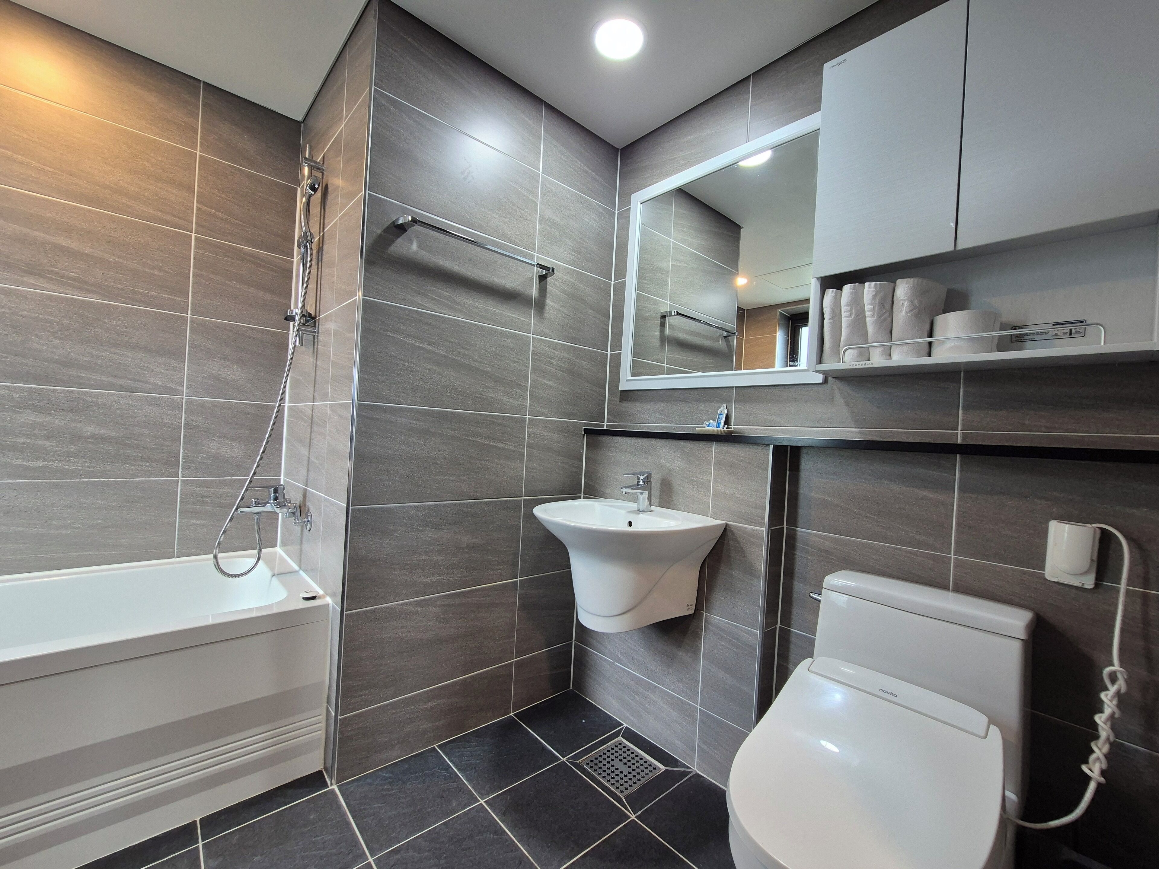 A modern bathroom with a bathtub, sink, toilet, and a mirror above the sink.