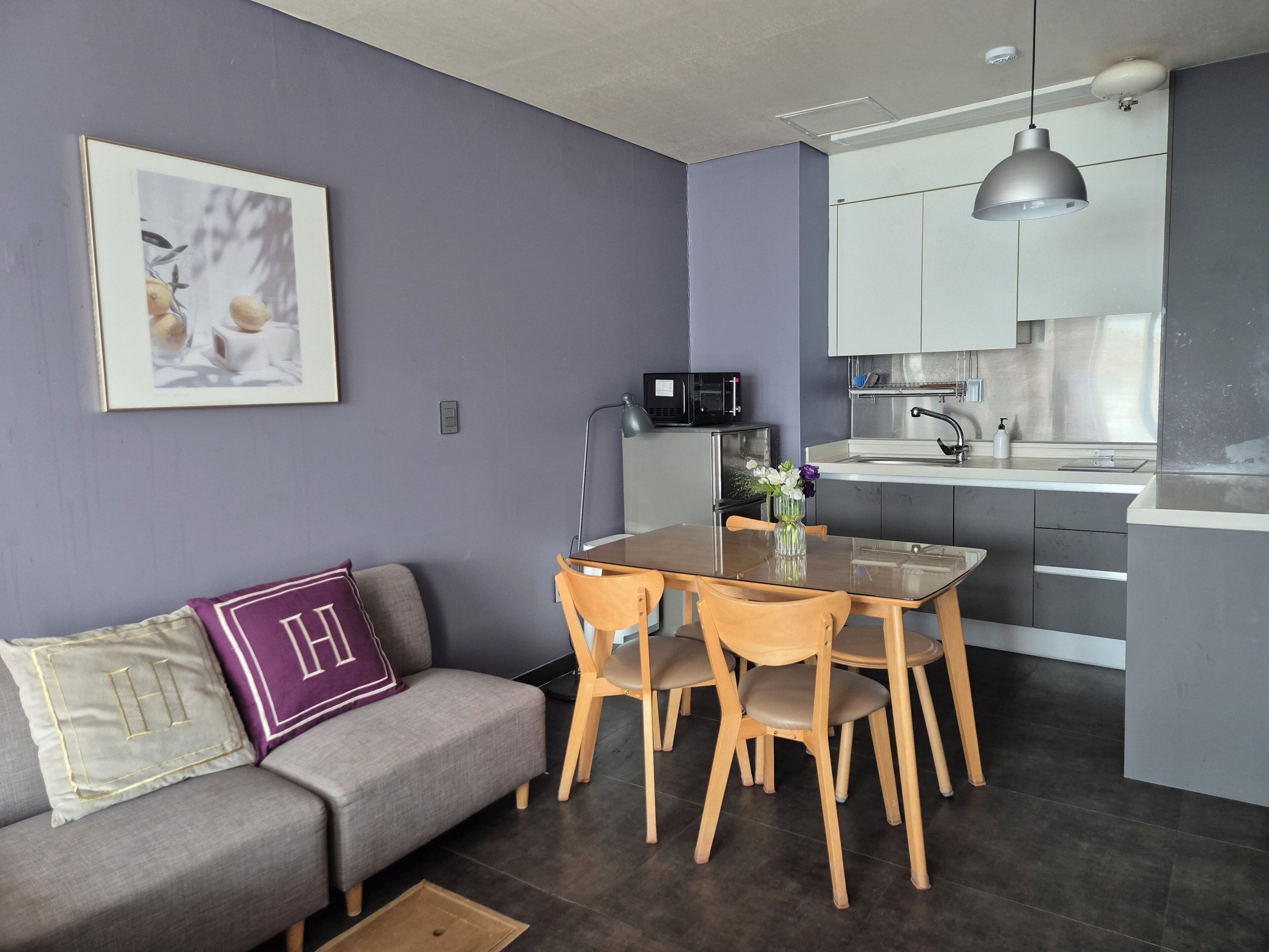 A modern kitchen with a dining table and chairs, a microwave, and a sink.