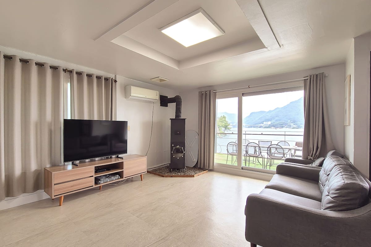 A modern living room with a flat-screen TV, wooden entertainment unit, and a sofa.