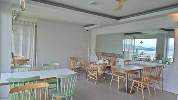 Un comedor con mesa y sillas, un ventilador de techo y vistas a través de una ventana.