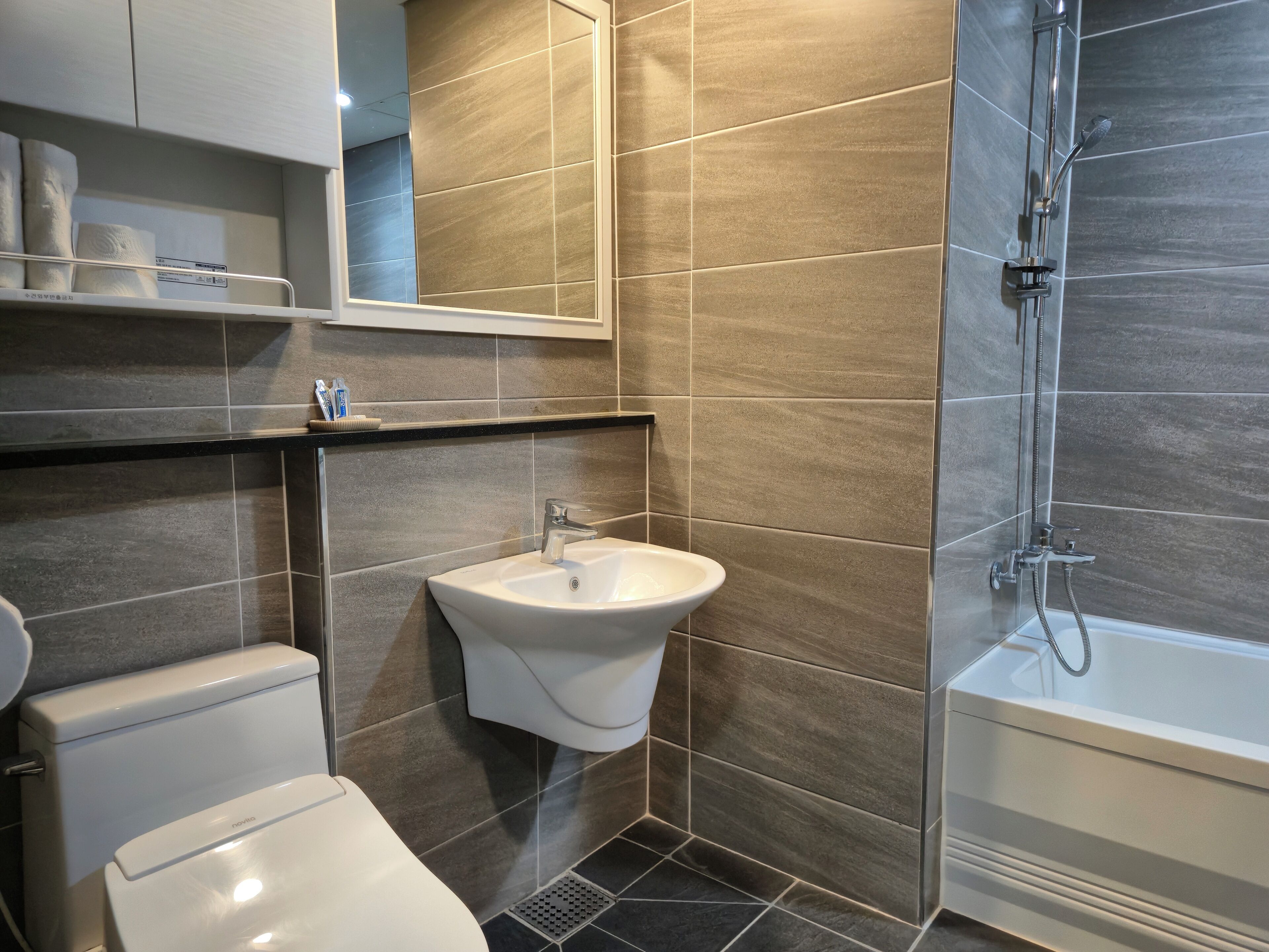 A modern bathroom with a toilet, sink, and shower.