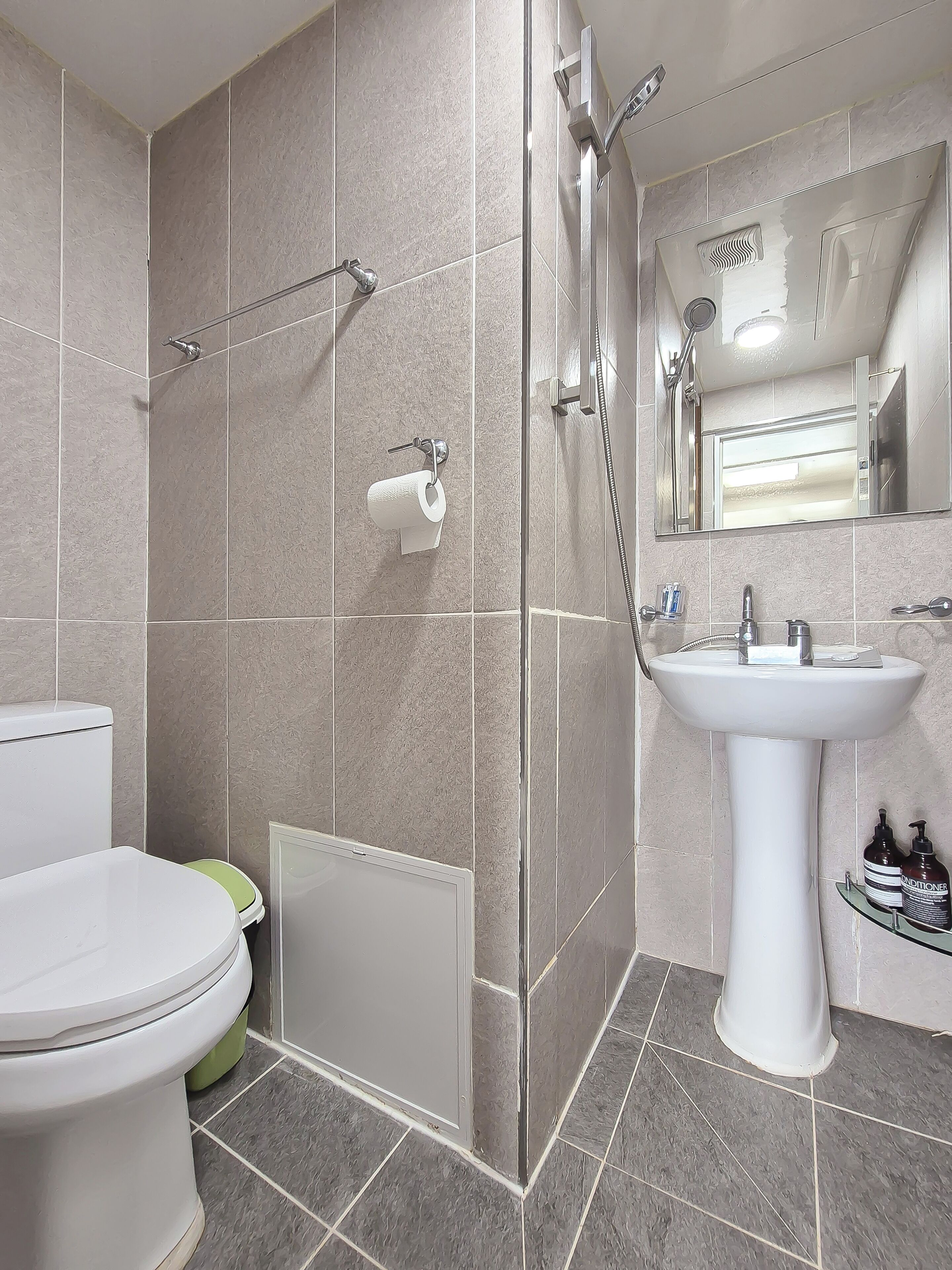 A bathroom with a toilet, shower, and sink.