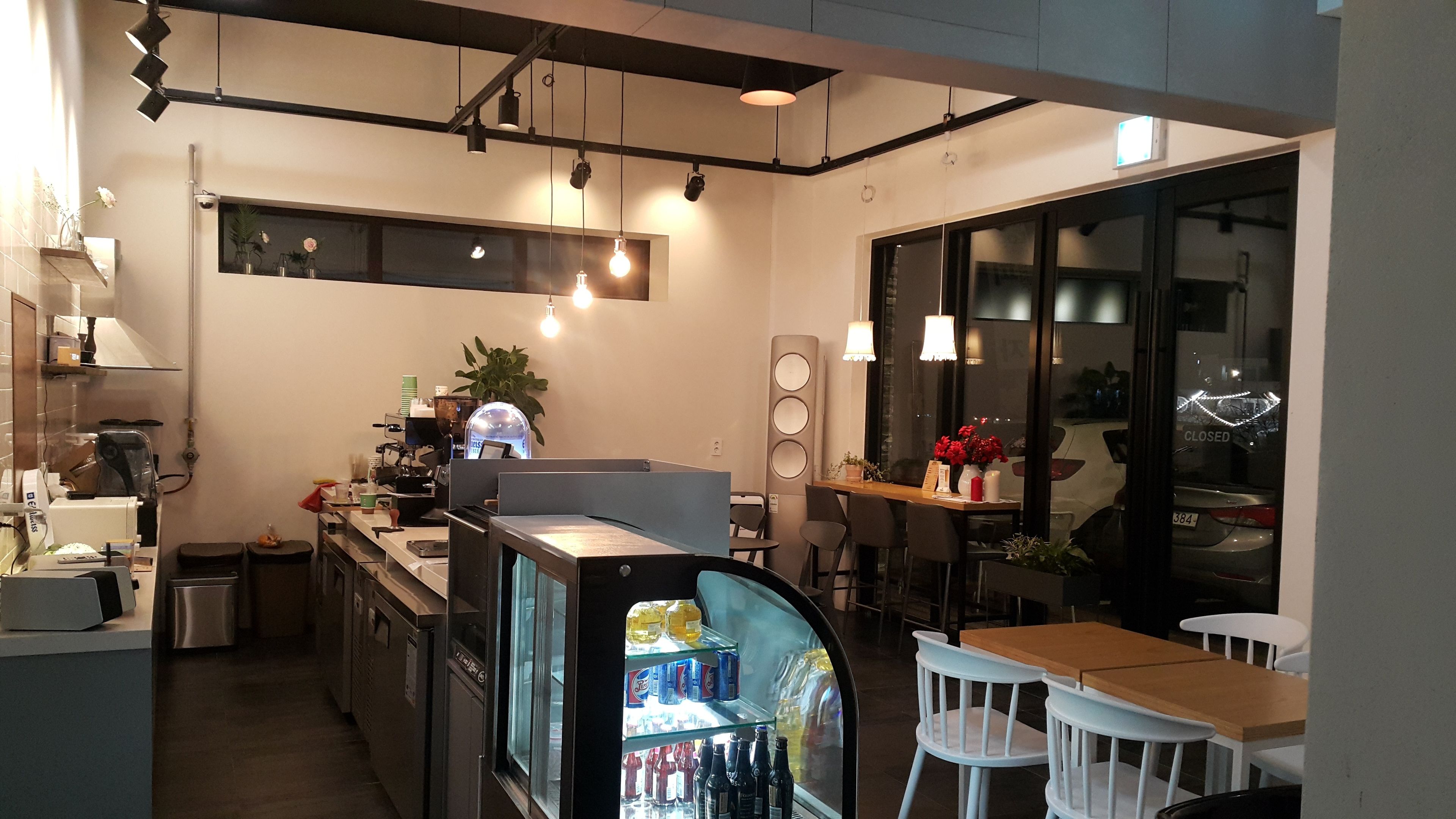 A compact kitchen with a refrigerator, coffee machine, and a small dining area with a table and chairs.