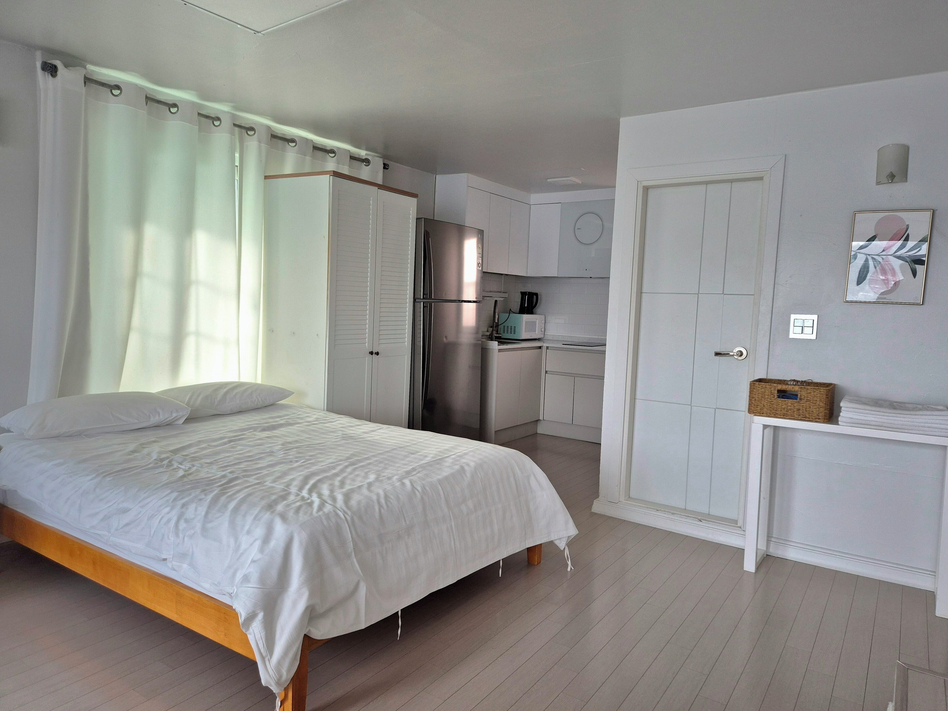A bedroom with a bed, a wardrobe, a kitchenette, and a bathroom.