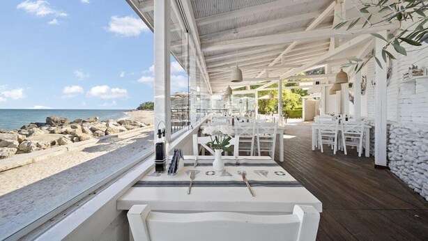 An outdoor dining area with white furniture and a view of the beach and ocean. - Hotel Riviera Beach AND SPA (Golden Sands)