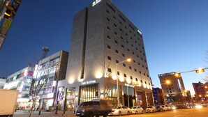 Un hotel de varios pisos con un llamativo letrero de 'Café D'Coffee', diseño arquitectónico moderno y una animada calle urbana.