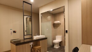 Un baño moderno con tocador de madera, un espejo grande, inodoro y zona de ducha.