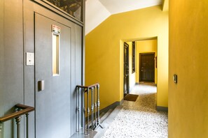 A hallway with a grey door, a yellow wall, and a staircase. - Italianway   - Corso Lodi 9 (Milan)