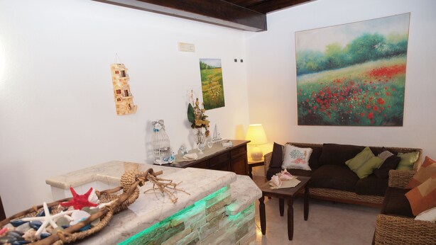 Un salon avec un mur en pierre, un canapé, une table basse et un tableau accroché au mur.