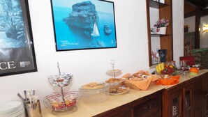 Un buffet garni de divers plats, une photo encadrée représentant un paysage côtier et une pancarte sur laquelle est inscrit le mot « TRAPANI ».