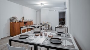 Un espace de restauration moderne avec plusieurs tables dressées pour les repas, un buffet en bois et, au fond, un coin cuisine.