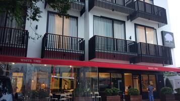Un edificio moderno con varios balcones, un toldo rojo y un letrero que dice "WHITE TREE RESIDENCE".