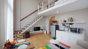 A modern apartment with a staircase, a kitchen, a dining area, and a living room. - White Tree Residence (Jakarta)