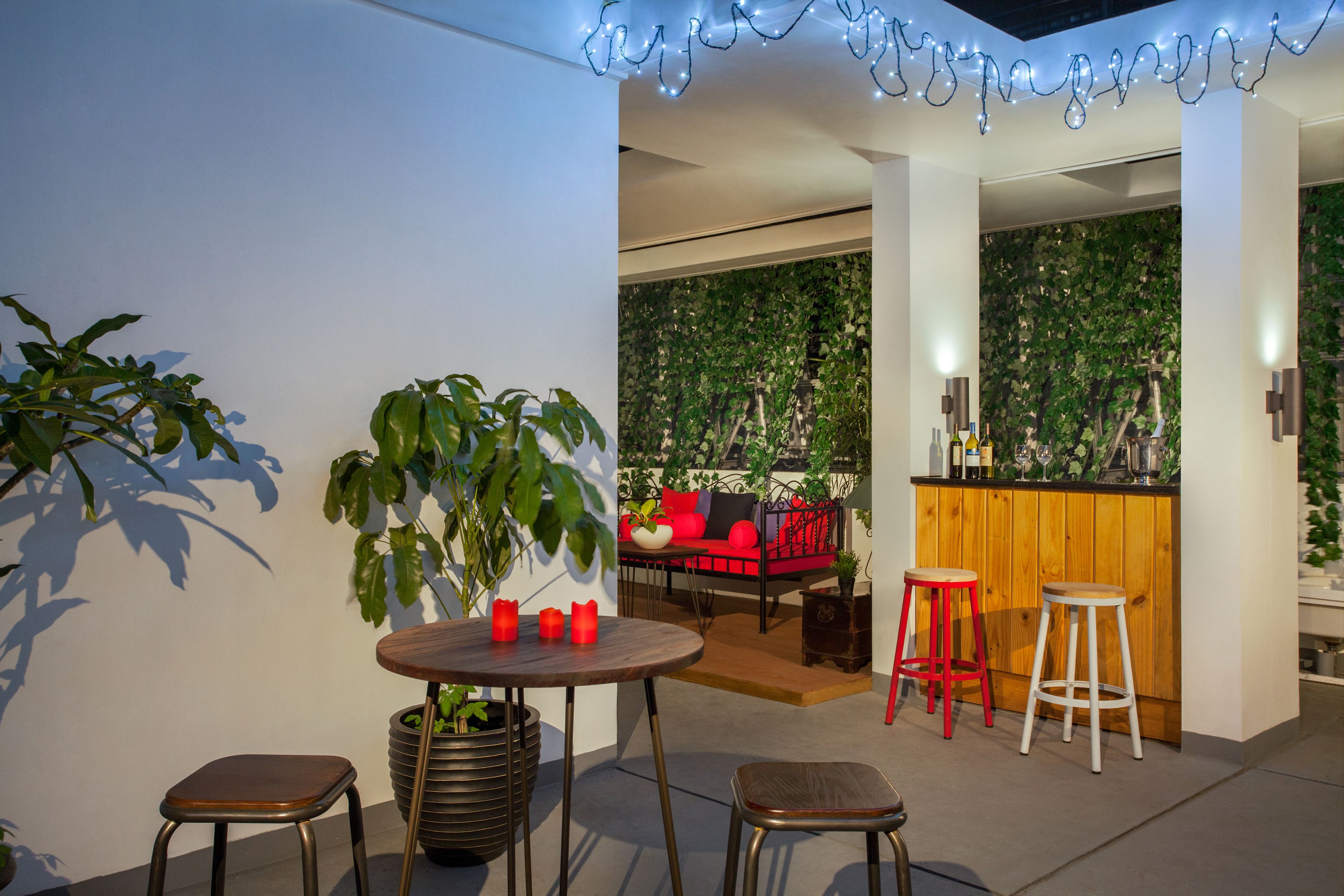 Un espacio exterior moderno con una mesa de madera, dos taburetes y una planta en maceta.