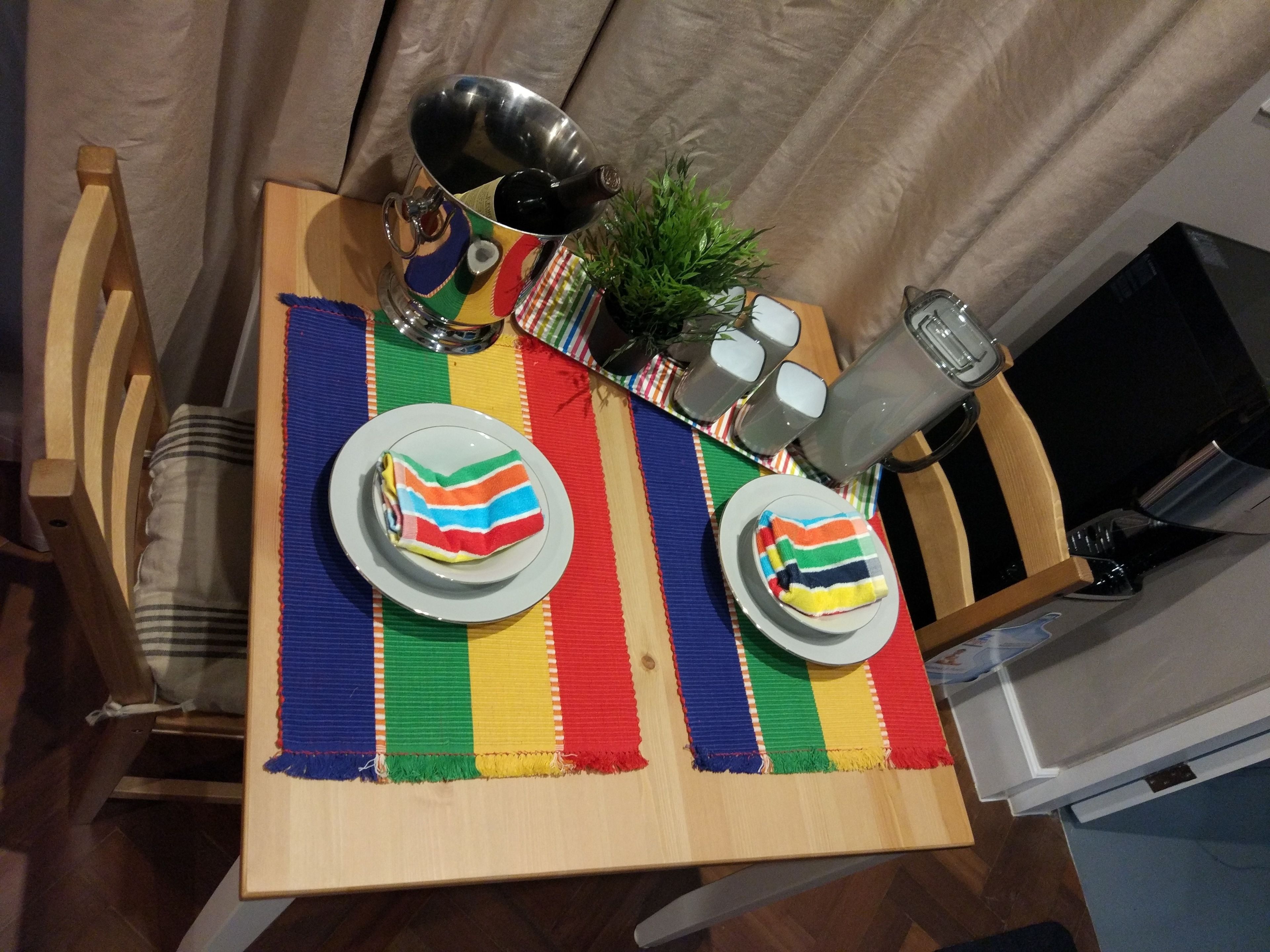 A dining table with two plates, a teapot, salt and pepper shakers, and a small plant.
