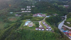 An aerial view of a residential area with houses, a swimming pool, and winding roads. - Daea Ulleung Resort (Ulleung)