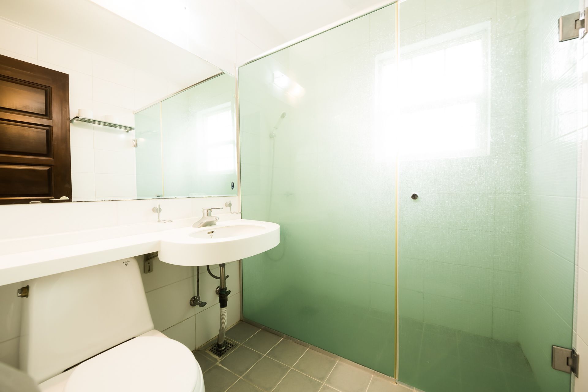 A bathroom with a white sink, a mirror, and a glass shower enclosure.