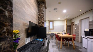 Una cocina moderna con un televisor de pantalla plana, una mesa de comedor con sillas y una planta pequeña en la encimera.
