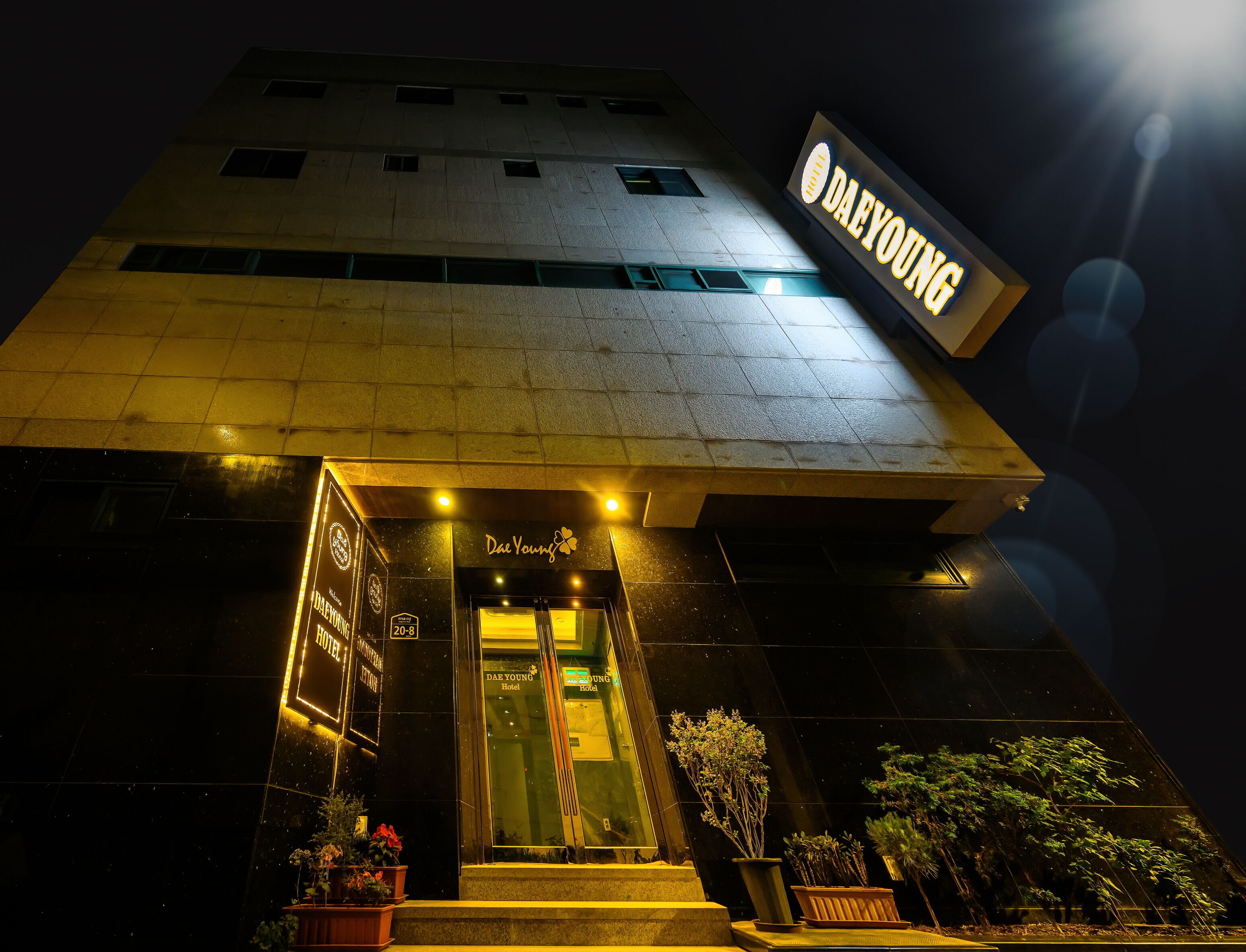 Exterior del hotel DAE YOUNG con un llamativo letrero iluminado, fachada moderna y una entrada bien iluminada.