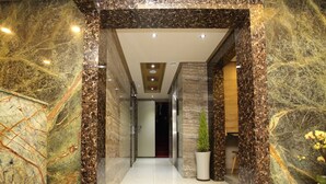 Un pasillo moderno con paredes de mármol y una planta en maceta.