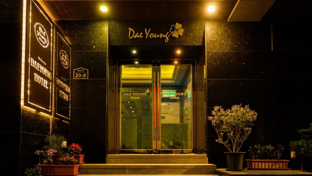 Exterior del hotel Dae Young con un letrero de bienvenida, una recepción y plantas en macetas en la entrada.