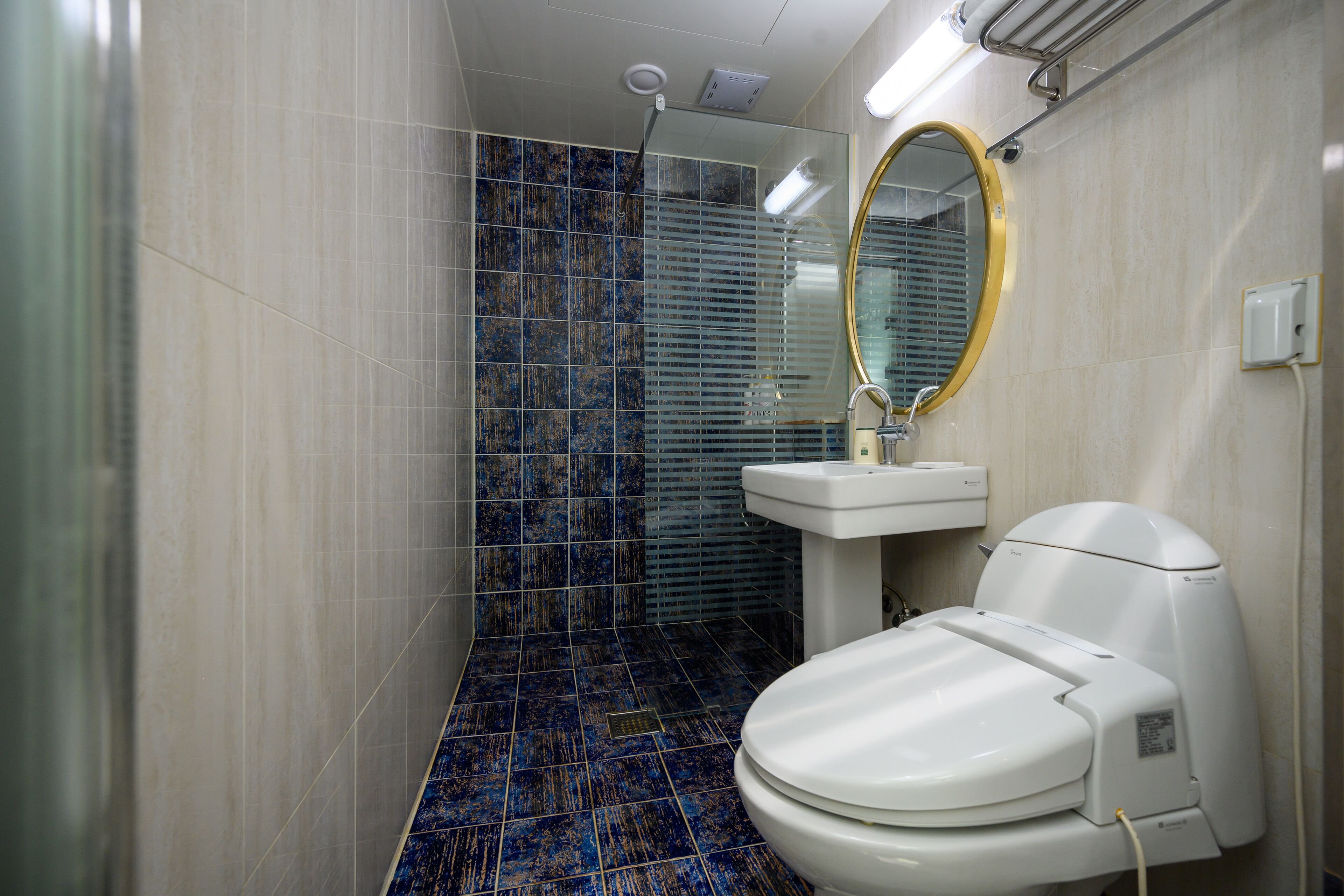 A bathroom with a white toilet, a sink, and a shower area with blue tiles.