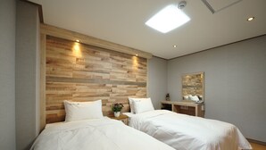 Habitación de hotel con dos camas, cabecero de madera, mesita de noche con un florero y un espejo en la pared.