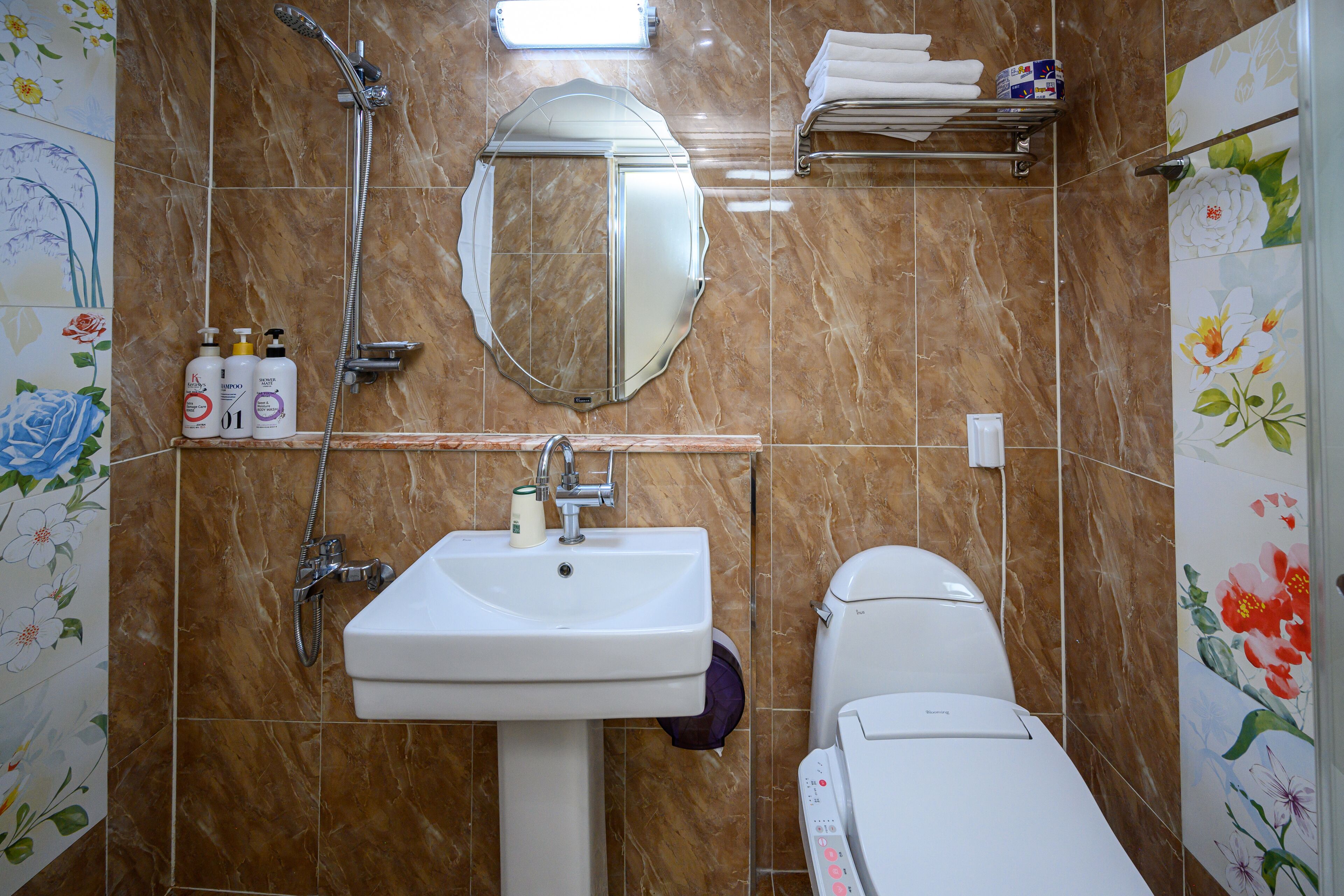 A bathroom with a sink, mirror, shower, toilet, and towel rack.