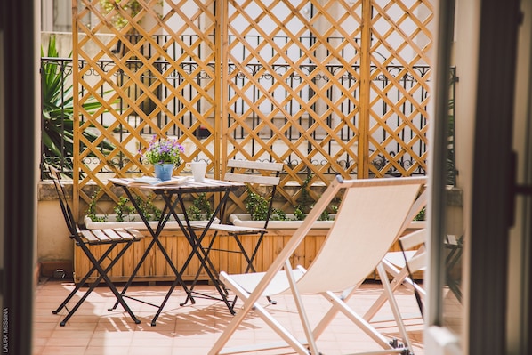 A patio area with a wooden lattice partition, a small table with a potted plant, and two white lounge chairs. - Dimore delle Zagare Ortigia (Syracuse)