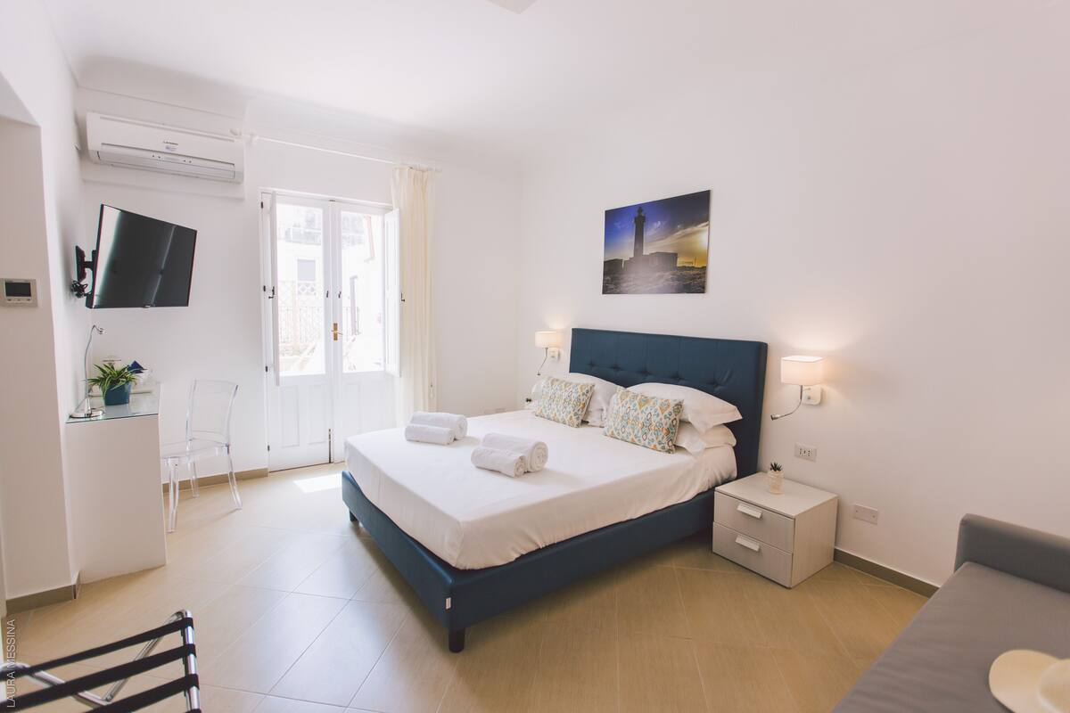 Une chambre à coucher moderne avec un lit, une table de chevet et un téléviseur fixé au mur.