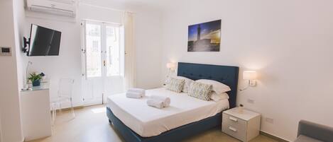 Un dormitorio moderno con una cama, una mesita de noche y un televisor montado en la pared.