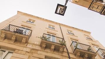 Un immeuble à plusieurs étages doté de balcons, de fenêtres et d’un lampadaire.