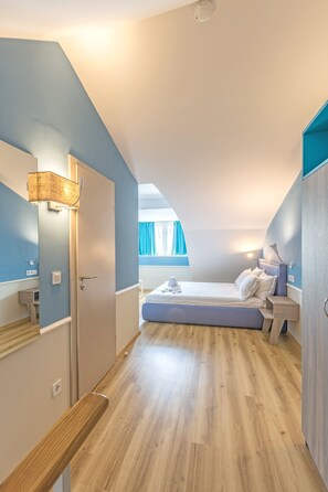 A bedroom with a wooden floor, a bed with white linens, a bedside table, and a window with curtains. - BSA Boulevard Boutique (Sunny Beach)