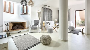 Un salon spacieux doté d’une cheminée, de meubles modernes et offrant une vue sur l’extérieur.