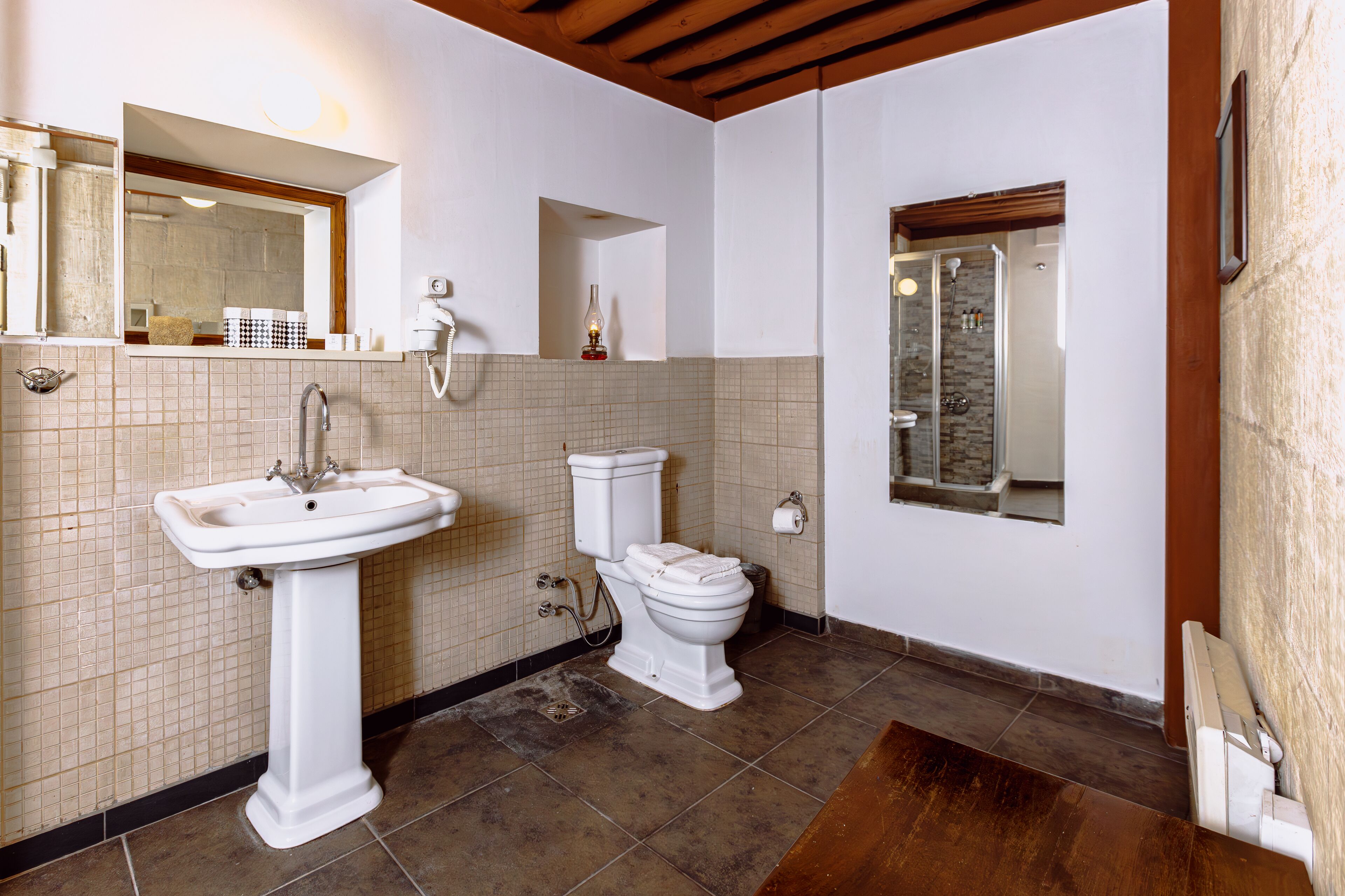 Un baño con lavamanos pedestal, inodoro y zona de ducha.