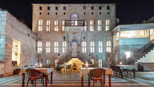 Un edificio histórico con patio de comidas, paredes de piedra y ventanas arqueadas.