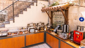 Una barra de desayuno con diversas opciones de comida, una máquina de café y vistas a la calle.